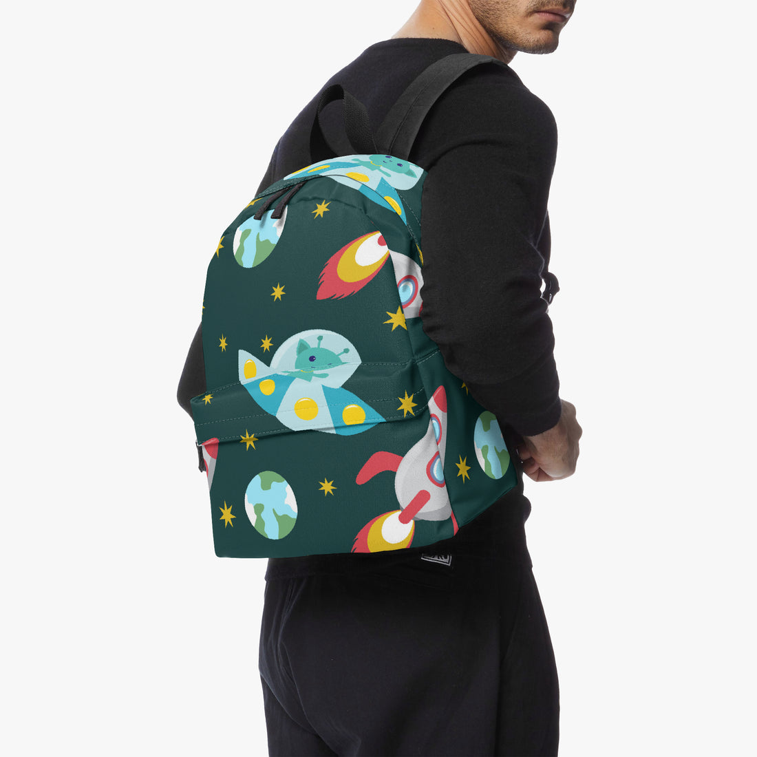 Space-themed canvas backpack on model; dark green with colorful rockets and planet print.