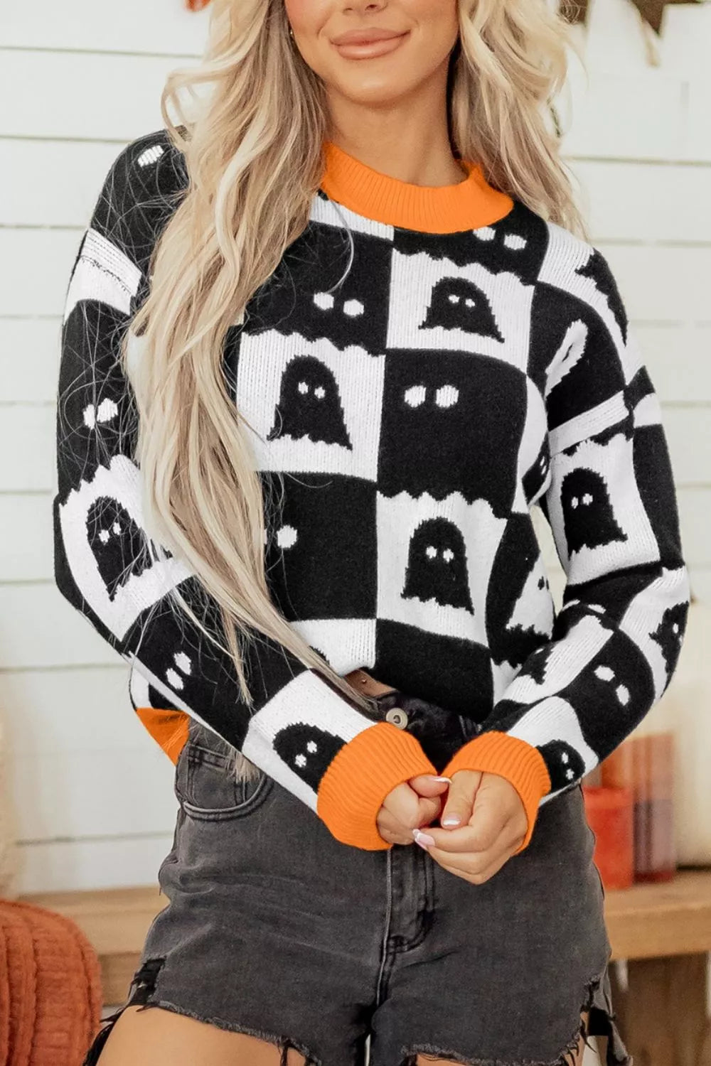 Ghost checkerboard knit sweater in black and white with orange ribbed crew neck
