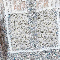 Off-white sleeveless woven lace top with button placket and blue floral print