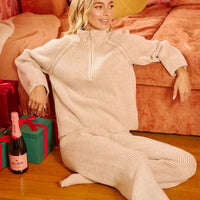 Taupe textured knit collared top with zip front and long sleeves, seated pose