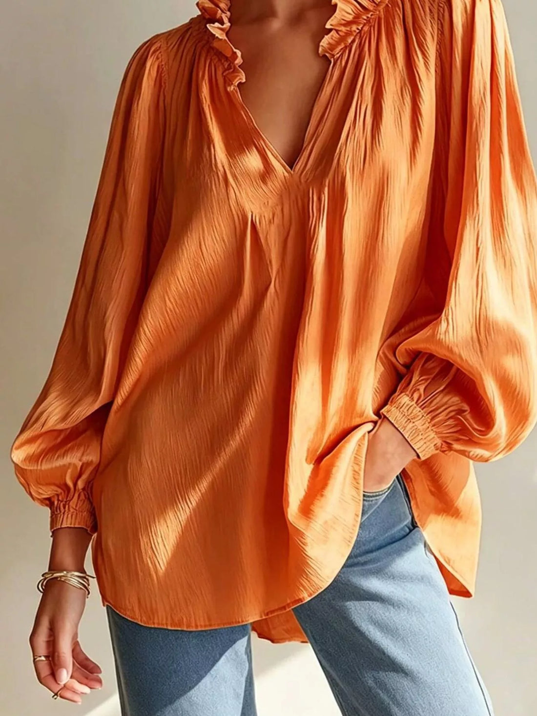 Tangerine ruffle-trim blouse with V-neck, puffed sleeves, and ruffled cuffs
