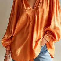 Tangerine ruffle-trim blouse with V-neck, puffed sleeves, and ruffled cuffs