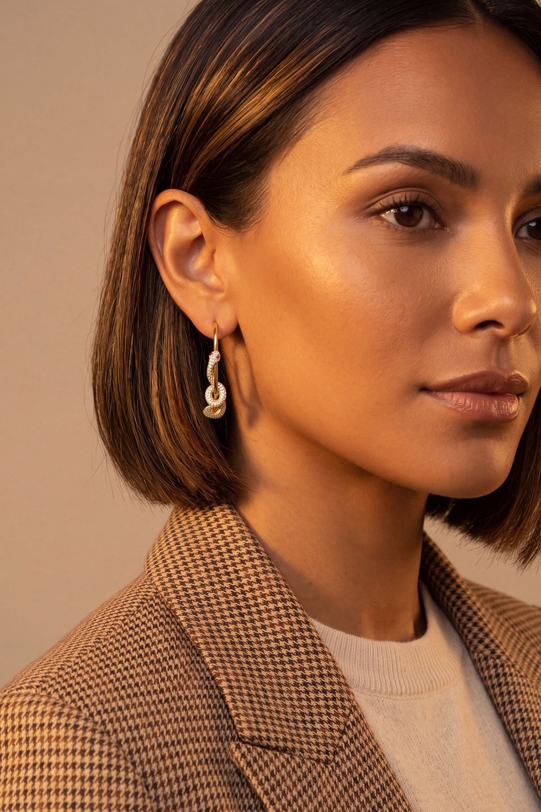 Gold snake hoop earrings with dangling sparkle details, worn by a model