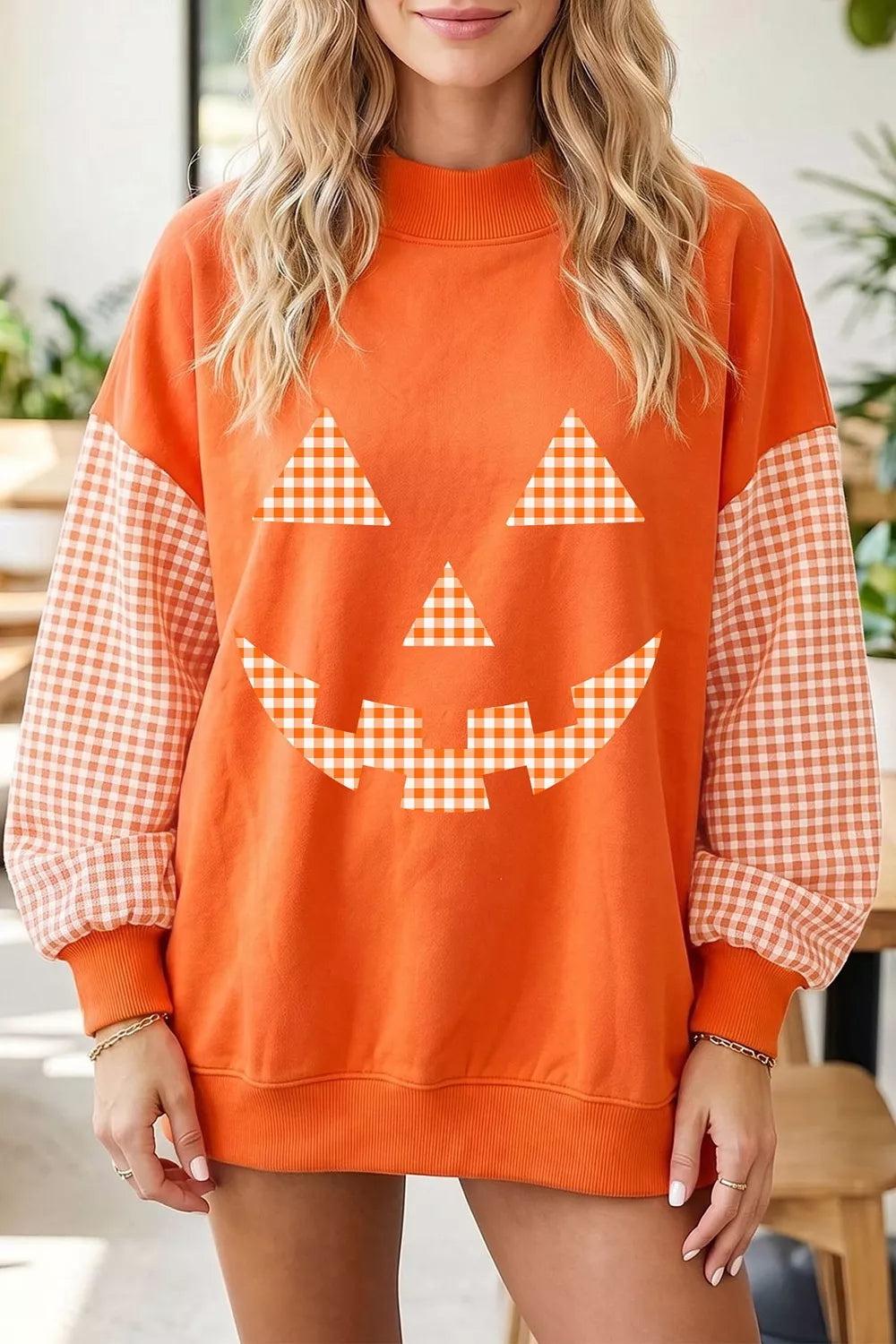 Orange sweatshirt with plaid pumpkin face graphic, long checkered sleeves