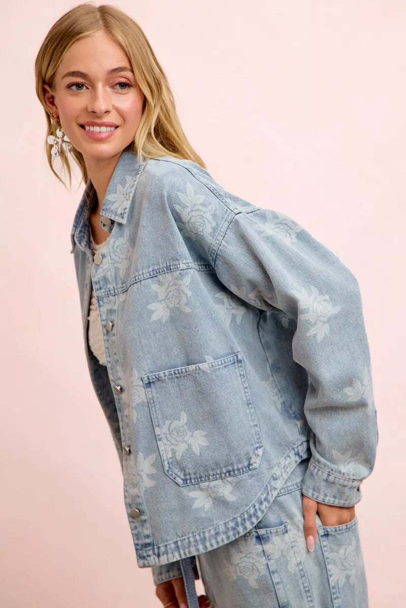 Light blue denim jacket with white floral print, chest flap pocket and rolled sleeve cuff