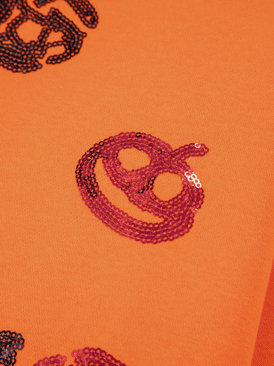 Orange sweatshirt close-up of red sequin mask and critter graphic
