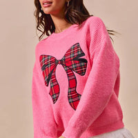 Pink knit sweater with plaid ribbon bow front and ribbed crew neckline