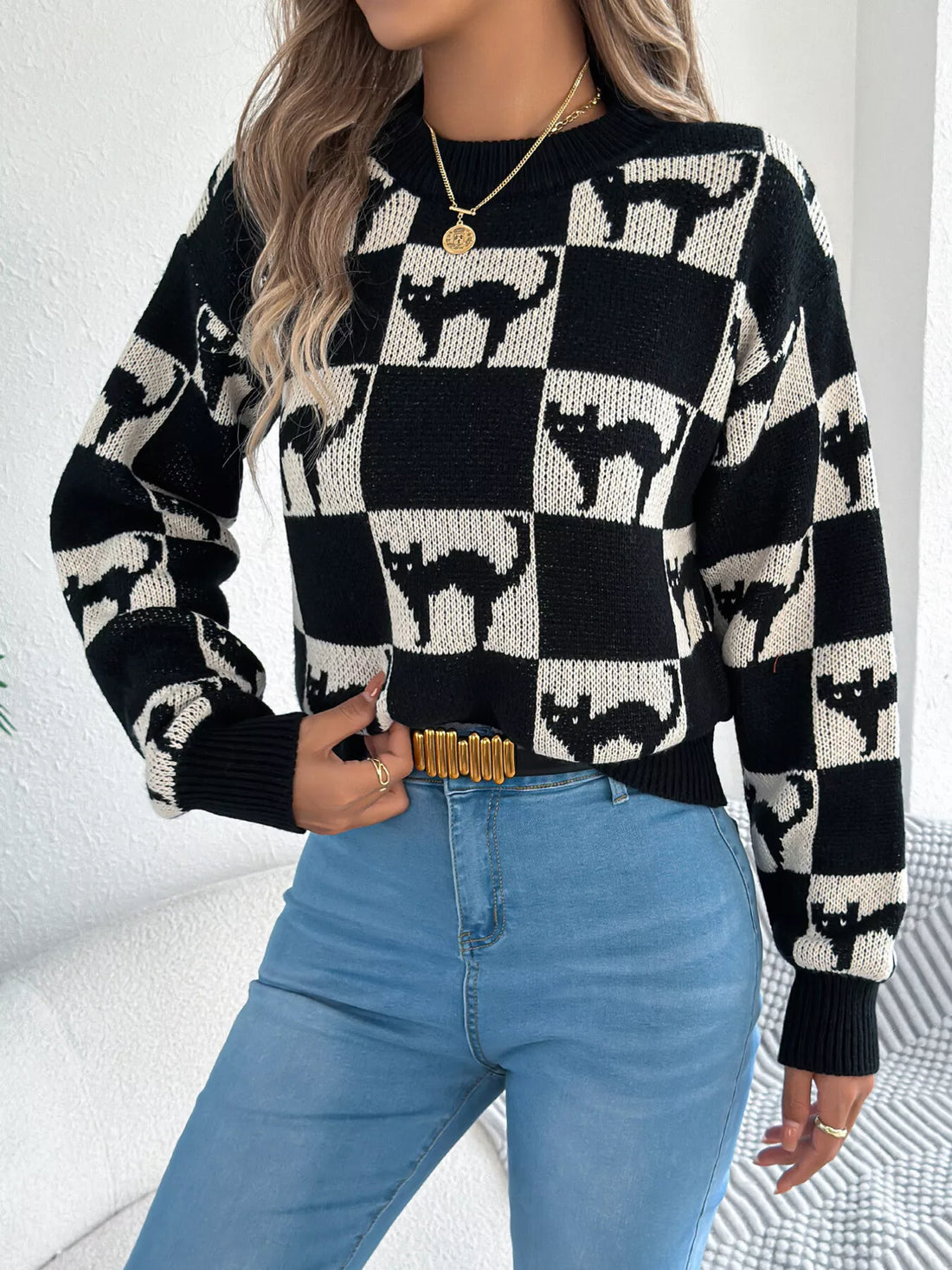 Side-front view: black and cream ghost checkerboard knit sweater with ribbed hem