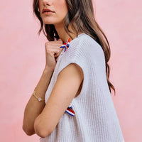 Off-white knit dolman sweater top with bow applique details on the sleeve and side