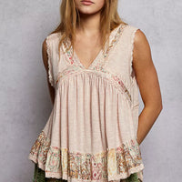 Pale pink sleeveless top with V-neck lace trim and ruffled floral hem