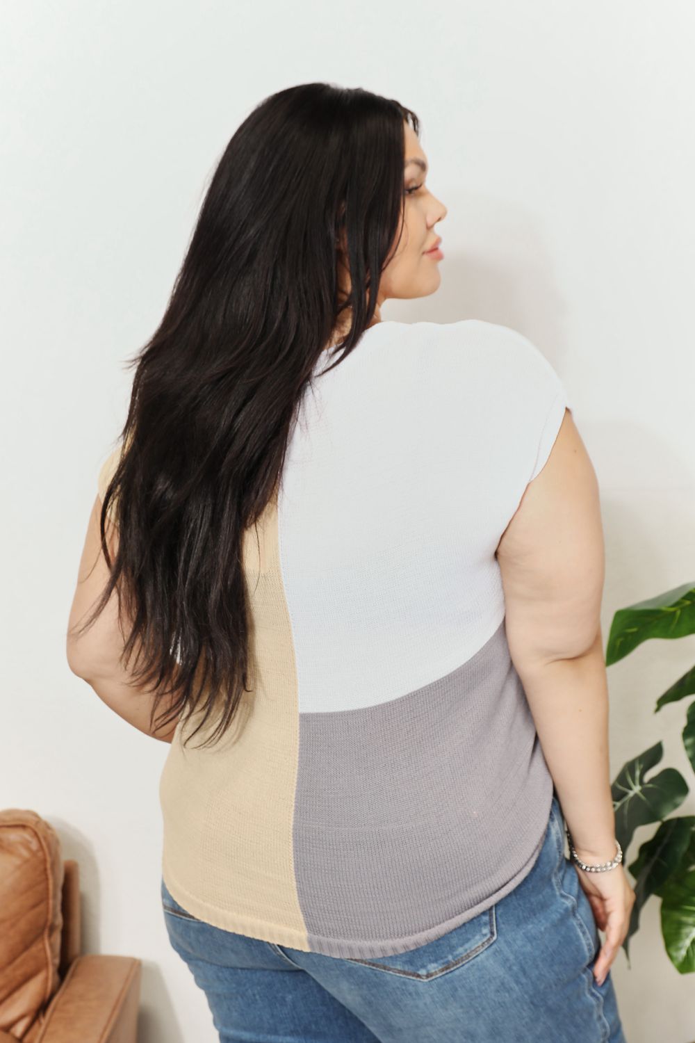 Back view of color-block knit top with V-neck back; beige and gray paneling