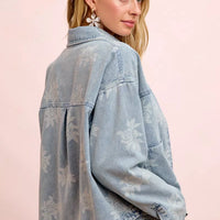 Light blue denim jacket with white floral print, shown from the back with yoke and seams
