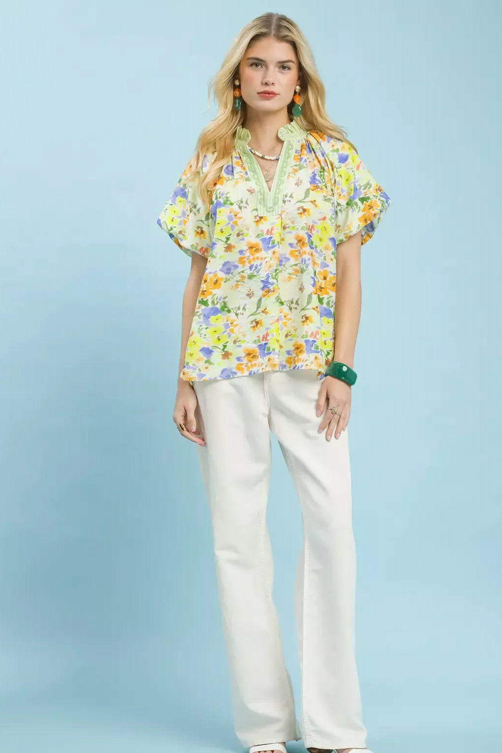 Green watercolor floral peasant blouse with V-neck and short sleeves, worn with white pants
