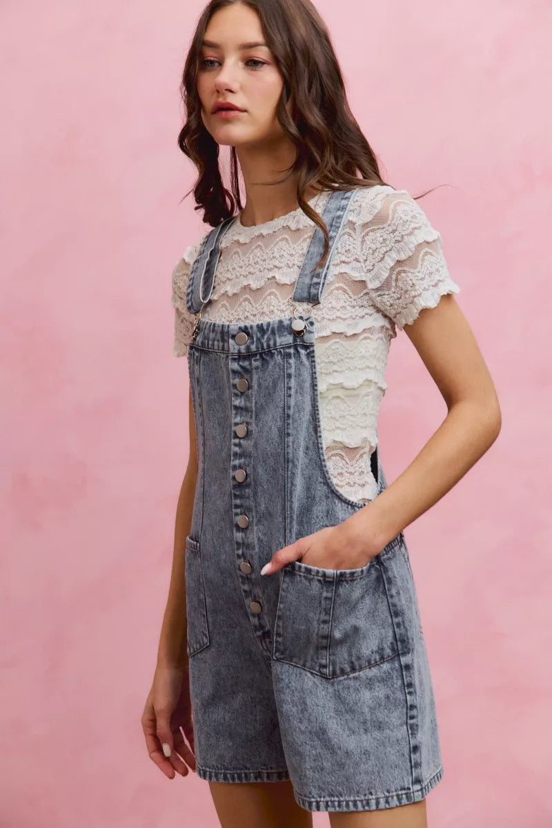 Light wash denim overall romper with adjustable straps, front buttons, and side patch pocket