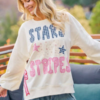 Cream sweatshirt featuring star-and-stripe patch lettering with red and blue bow details.