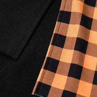 Close-up of black sleeve hem with orange and black plaid patch panel
