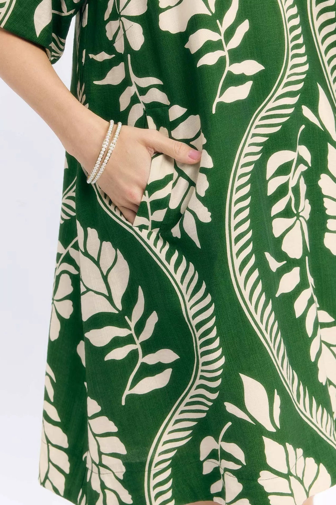 Close-up of green mini dress fabric with cream leafy and stripe pattern
