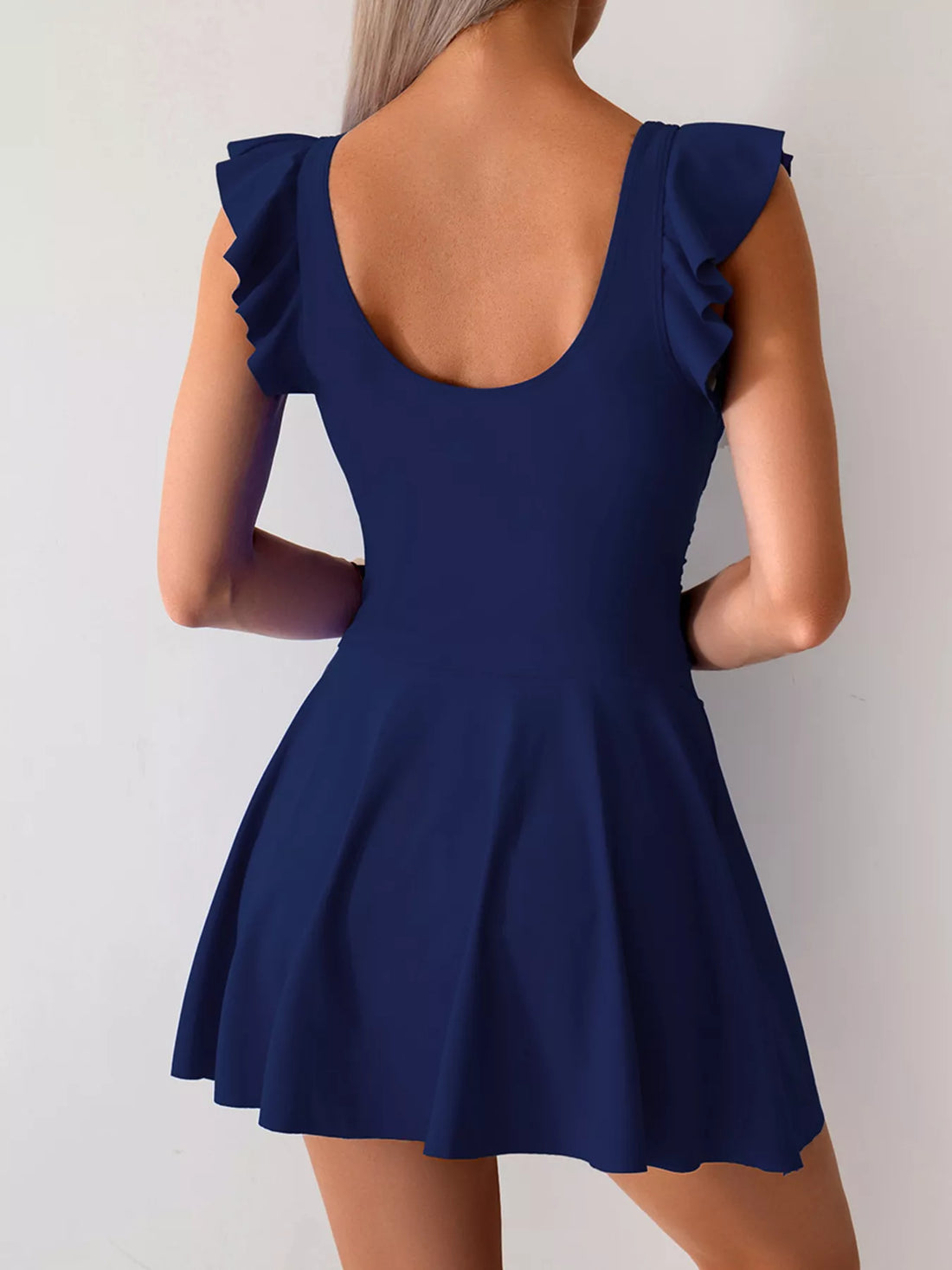 Royal blue ruffled-sleeve swim dress from back view, ruched waist, flared skirt with slit.
