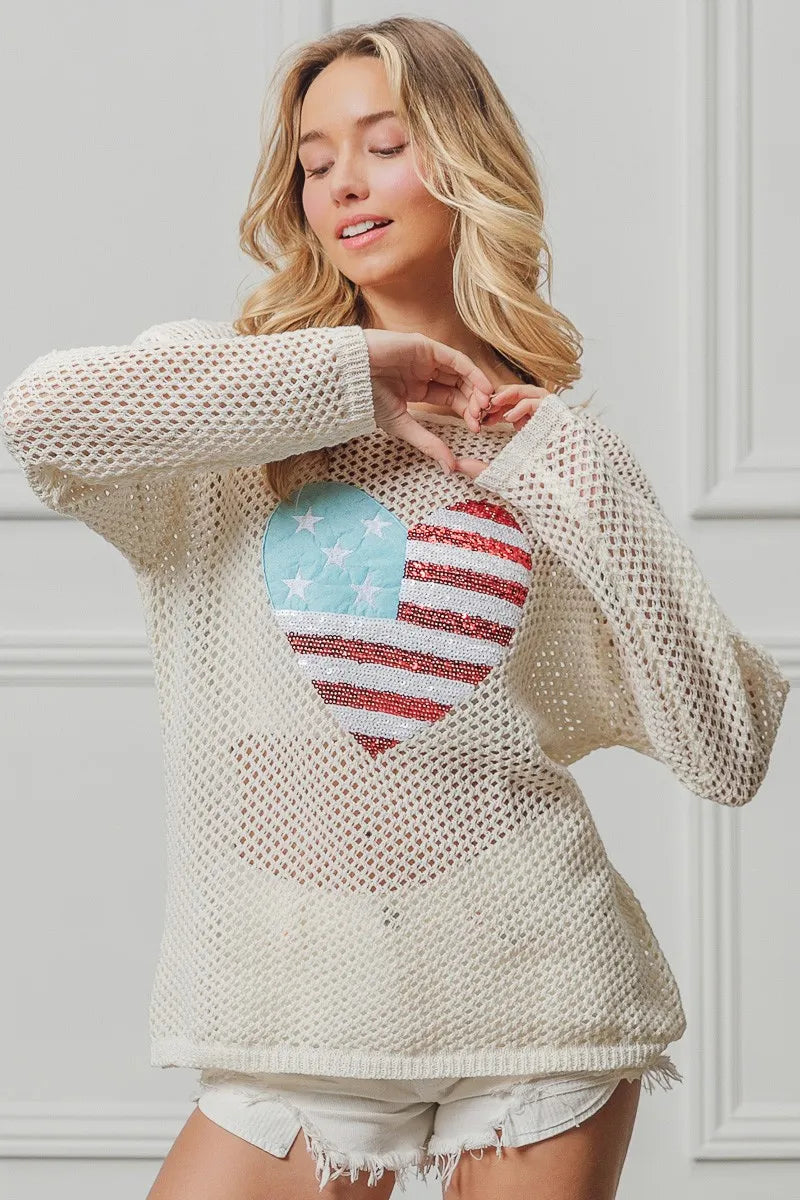 Off-white sequin knit sweater with American flag heart patch, long sleeves.