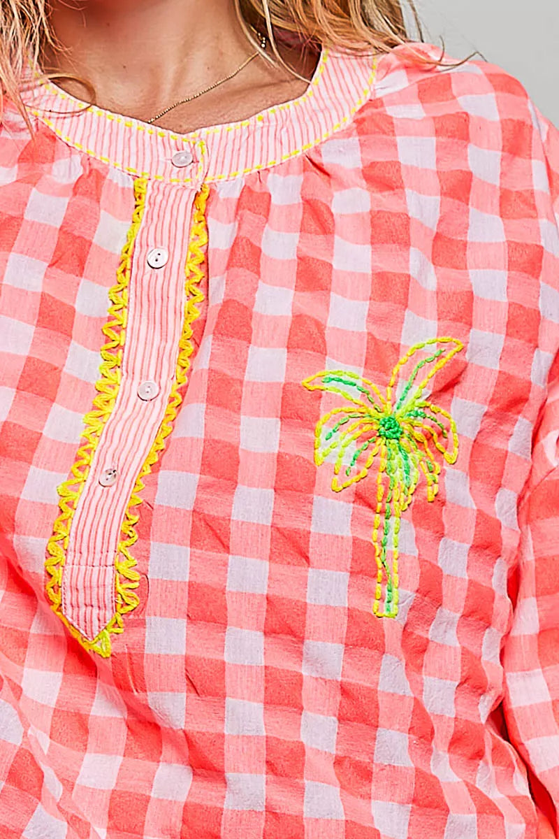 Pink gingham blouse close-up with palm tree embroidery and multicolor trim
