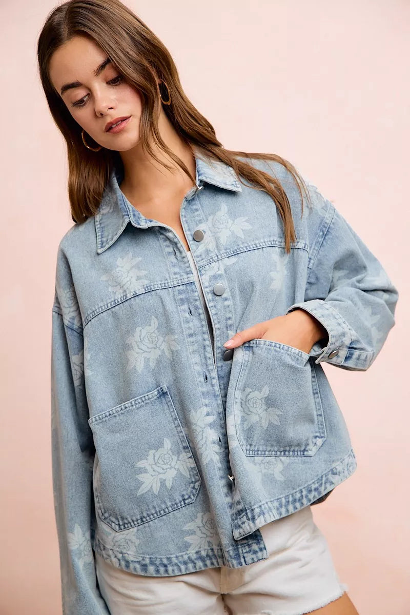 Light blue denim jacket with white floral print, button front, and chest flap pockets