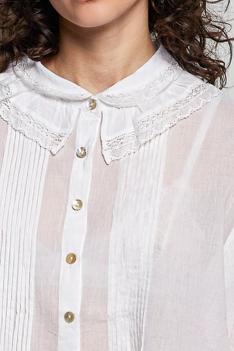 Close-up of ivory button-down collar with lace trim and gold-tone buttons