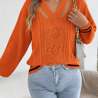 Orange cutout cable knit sweater with knit floral motifs and striped cuffs