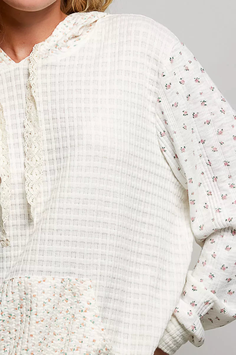 Cream knit hoodie close-up with floral-print sleeve and textured waffle fabric