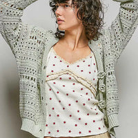 Light gray open-knit cardigan back with repeating lattice pattern and long sleeves