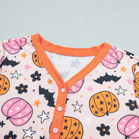 Close-up: dusty pink pumpkin-print long-sleeve top with orange V-neck button placket