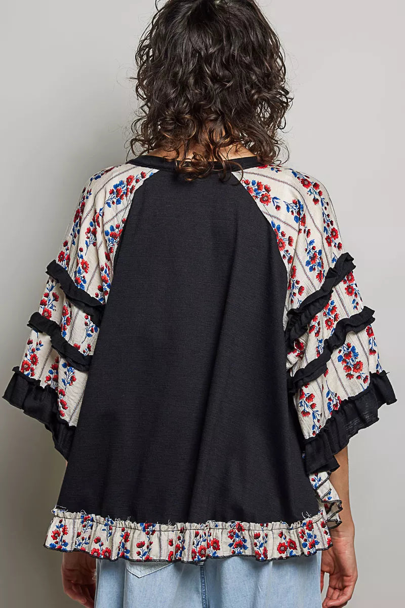 Black knit top back view with floral ruffle sleeves and contrast chevron lace panel