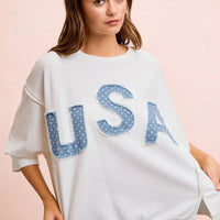 Ivory french terry pullover with blue "USA" patch letters and side slits near hem