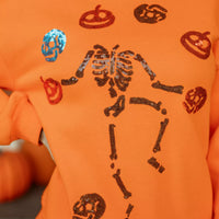 Orange sweatshirt close-up: sequin skeleton and icons across the front