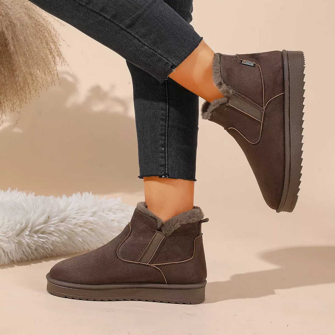 Dark brown plush-lined ankle boots with decorative seam lines and rubber traction sole