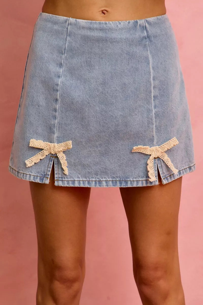 Light blue denim mini skirt with lace ribbon bow trim at the front hem.