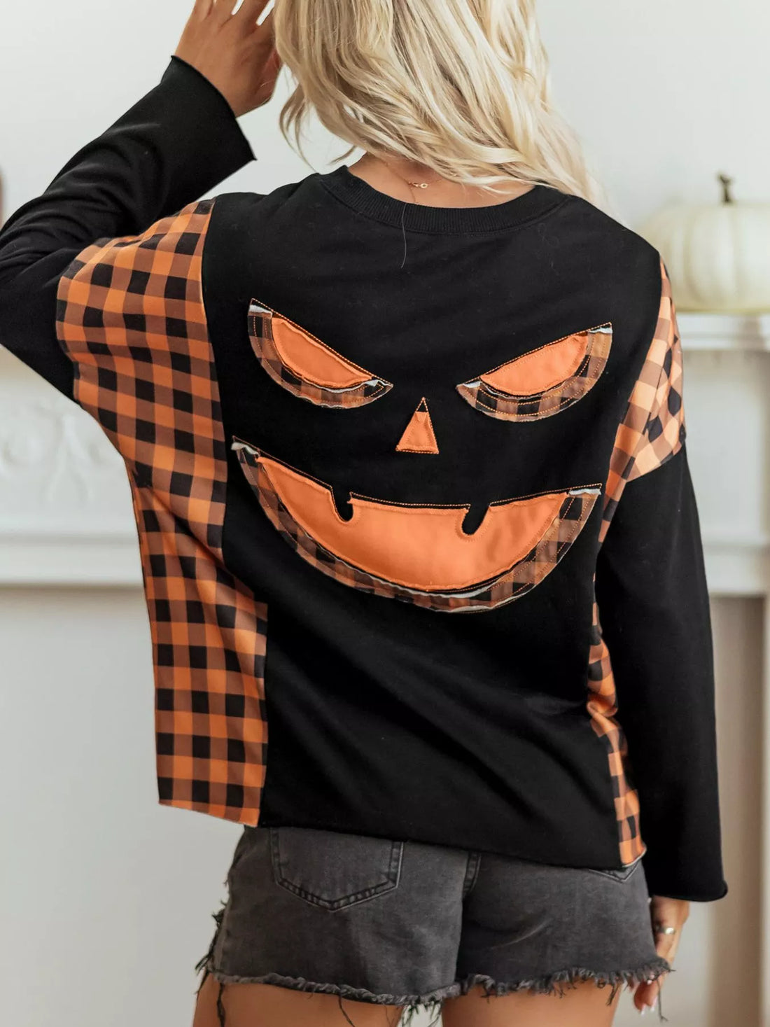Black long-sleeve top with orange plaid pumpkin face graphic on the back