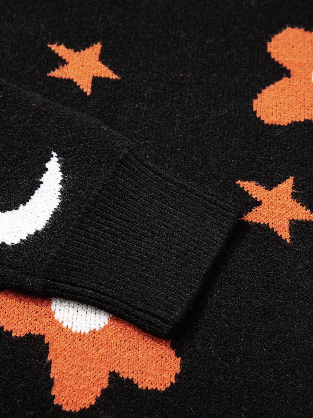 Black sweater cuff and hem with ribbed knit and orange star and flower pattern