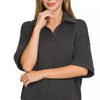 Black collared short-sleeve pullover with relaxed fit and half-zip neckline