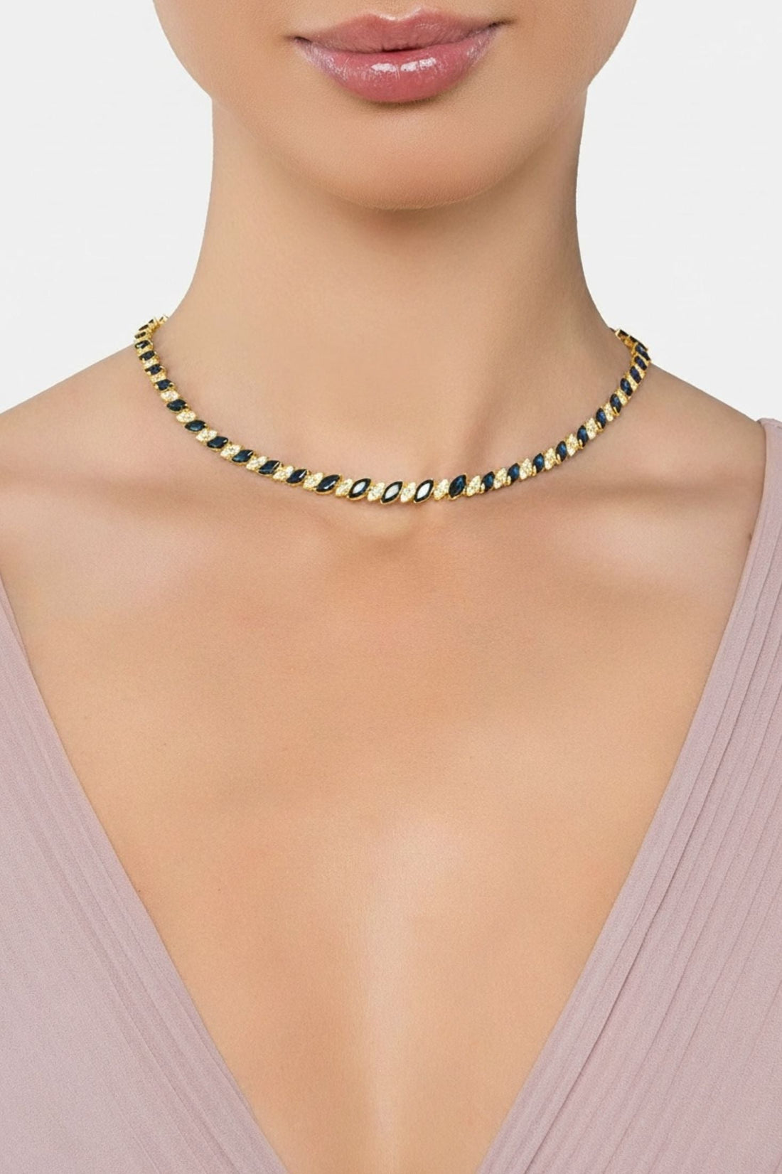Gold tennis necklace with dark blue oval stones on a model’s neck