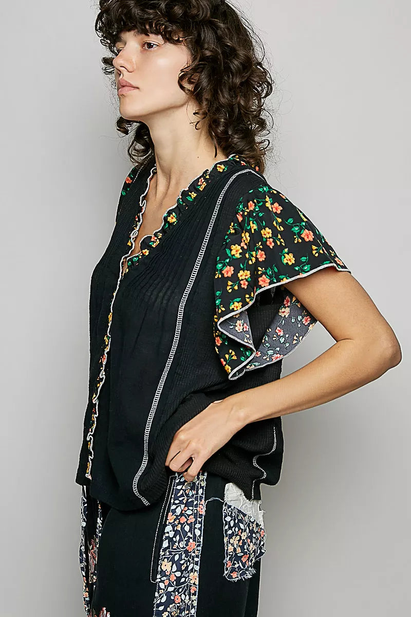 Black V-neck blouse with ruffle sleeves and floral print trim, side view