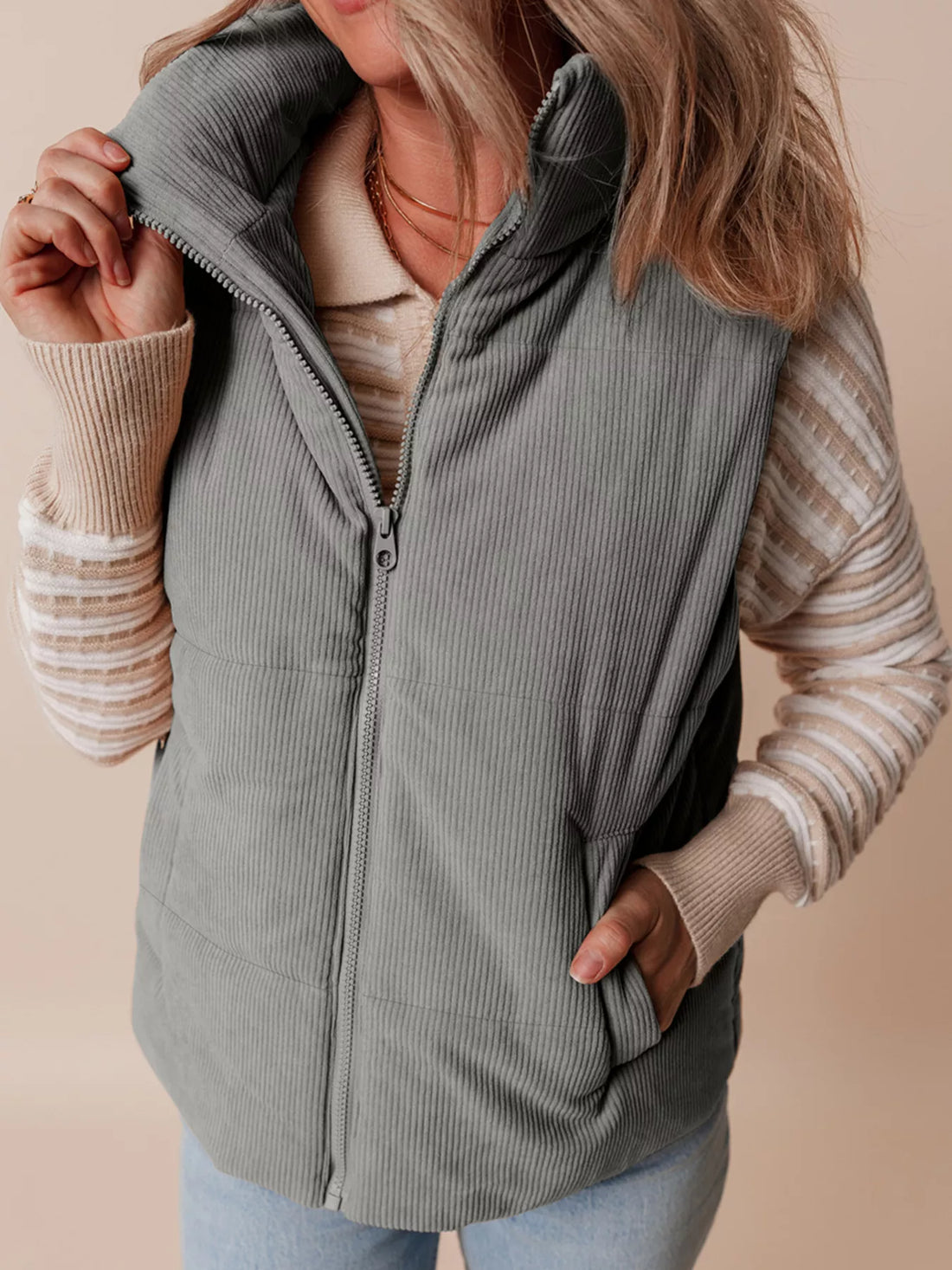 Gray corduroy stand-neck zipped puffer vest with full zipper and side pockets.
