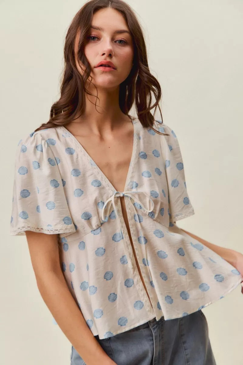 Ivory dot-print tie-front blouse with flutter sleeves and V-neck trim.
