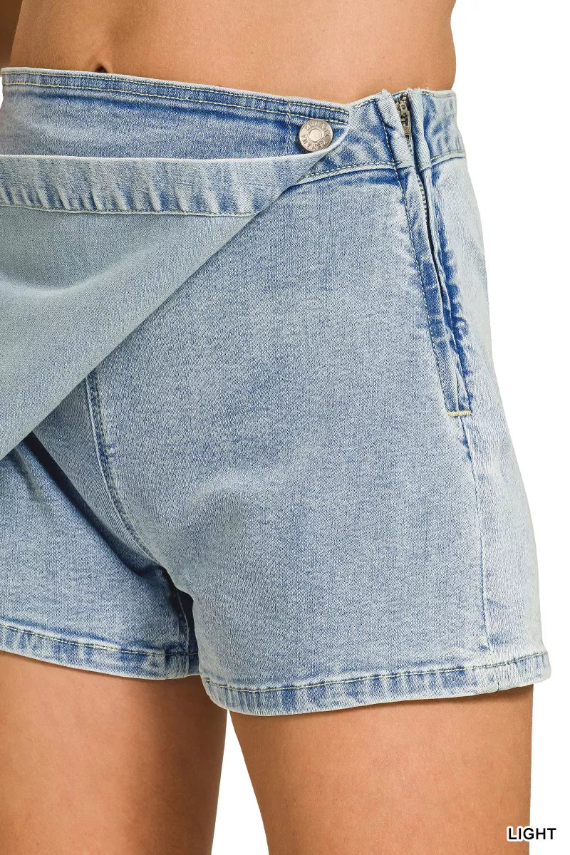 Light wash denim skort detail showing wrap flap and button at waistband