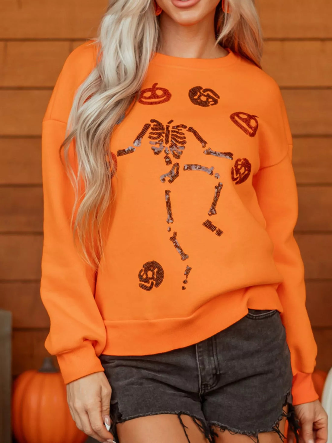 Orange crewneck sweatshirt with sequin skeleton and candy icons graphic, long sleeves