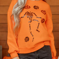 Orange crewneck sweatshirt with sequin skeleton and candy icons graphic, long sleeves