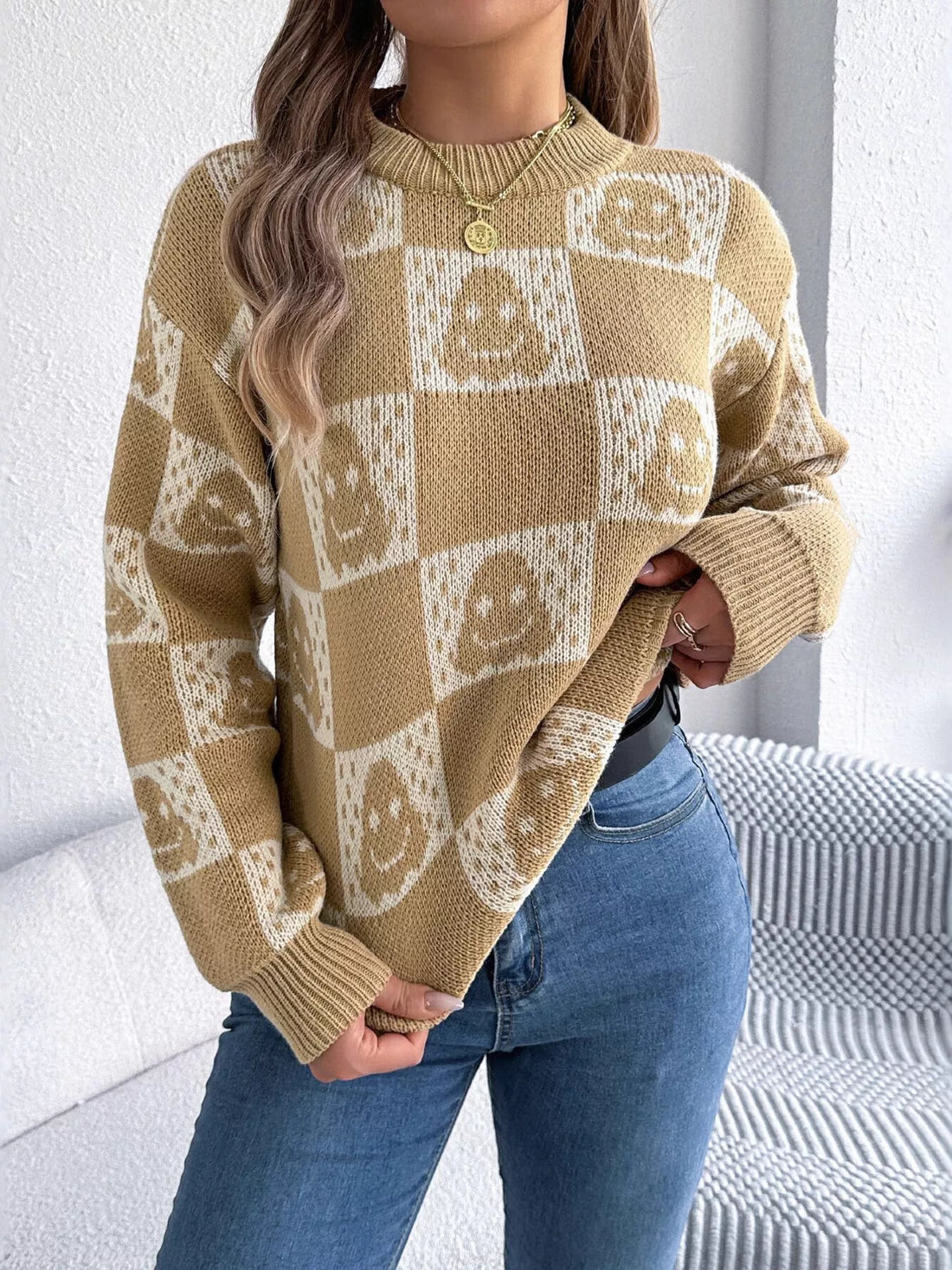 Front view: beige checkerboard Halloween graphic sweater with jack-o-lantern face motifs