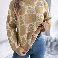 Front view: beige checkerboard Halloween graphic sweater with jack-o-lantern face motifs