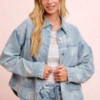 Light blue washed denim jacket with white floral print, button front, and flap pockets