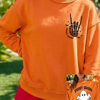 Orange mock neck sweatshirt with skeleton-hand 'Spooky Season' graphic, long sleeves