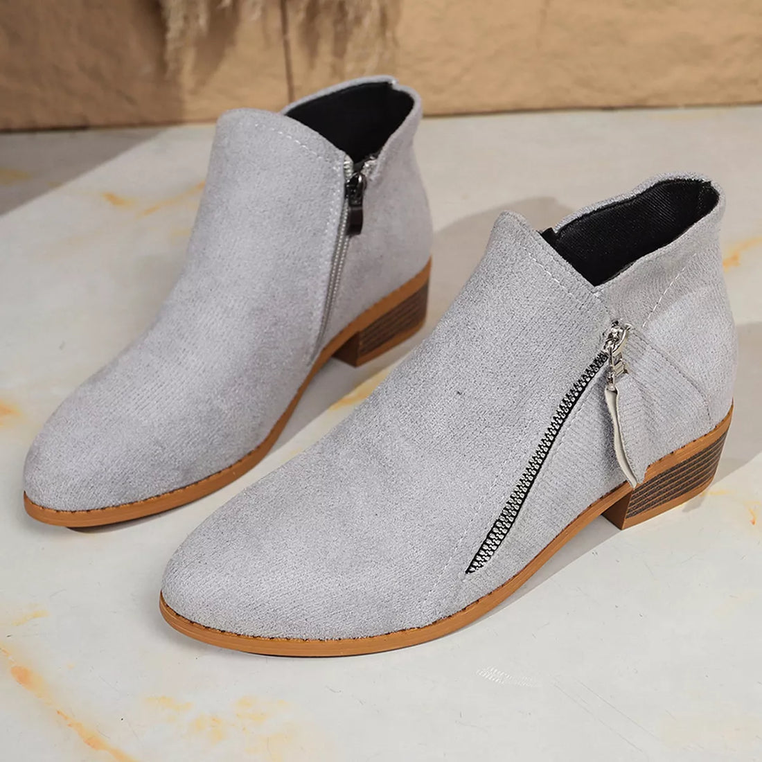 Light gray point-toe block heel ankle boots with side zipper and textured heel